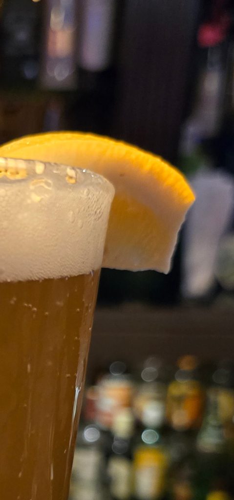 Blue Star Wheat Beer with a slice of lemon in a pint glass.